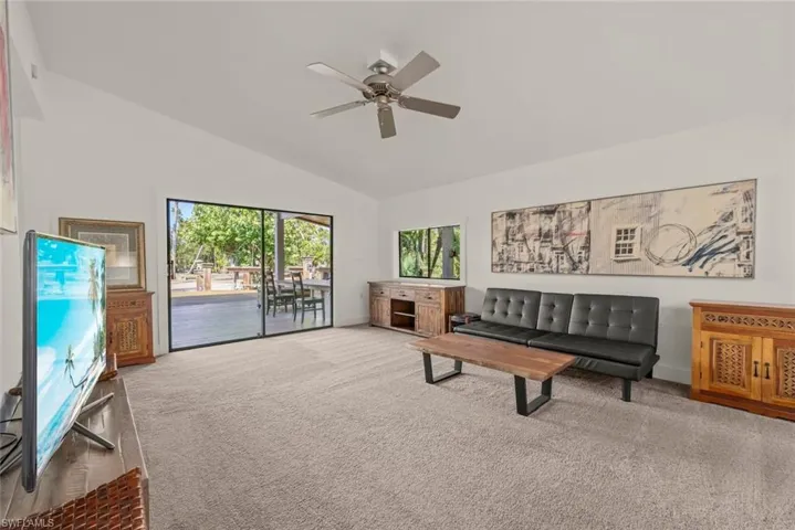Carpeted living area featuring a ceiling fan and lofted ceiling