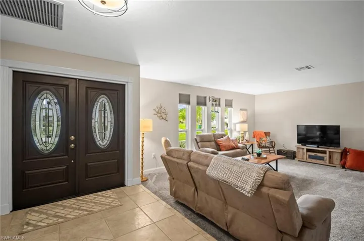Foyer featuring light tile patterned flooring and light colored carpet