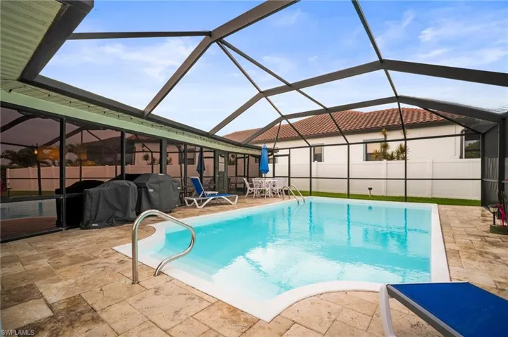 View of pool with a patio area and glass enclosure