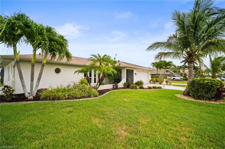 Ranch-style house with stucco siding, driveway, a garage, and a front lawn
