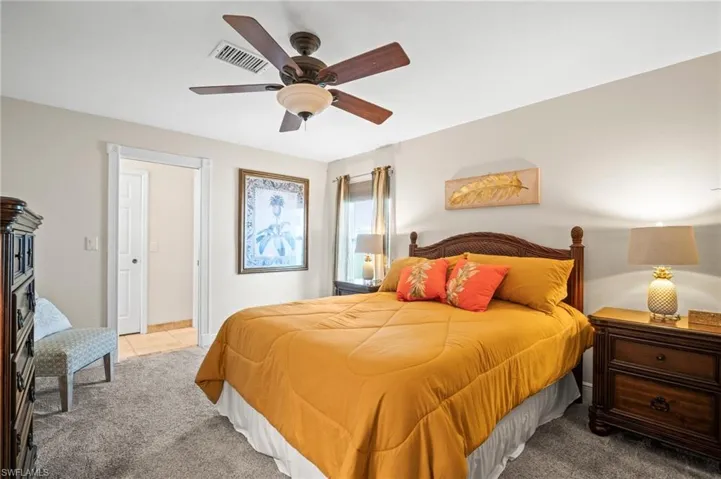 Carpeted bedroom with ceiling fan and tile patterned floors