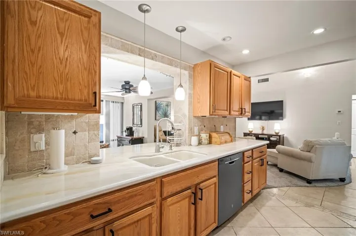 Kitchen featuring dishwashing machine, light countertops, decorative backsplash, ceiling fan, and pendant lighting