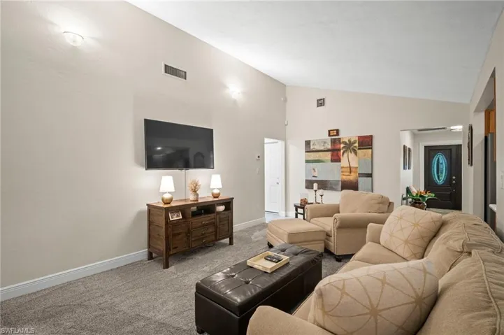 Carpeted living area featuring baseboards and high vaulted ceiling