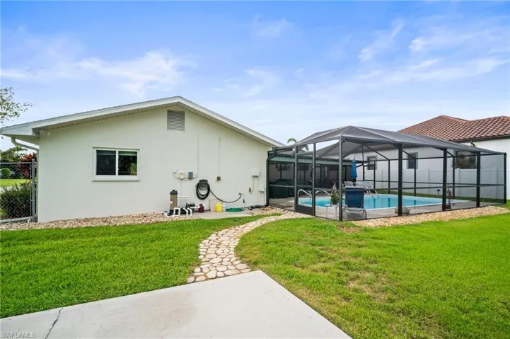Rear view of house with stucco siding, a lawn, and a patio