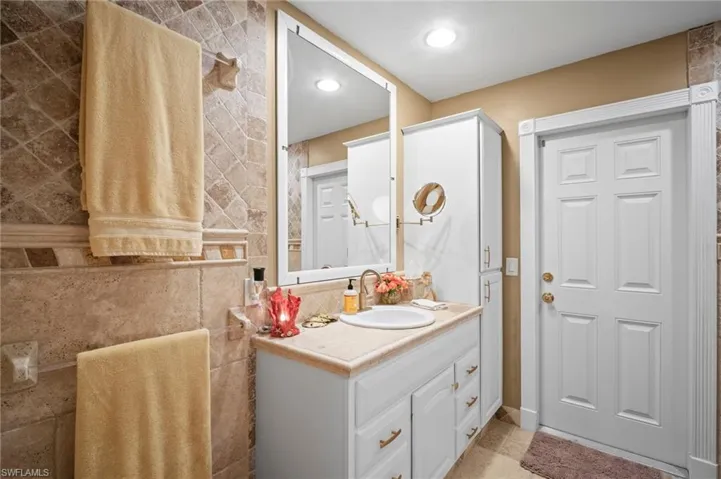 Bathroom with vanity, tile walls, and recessed lighting