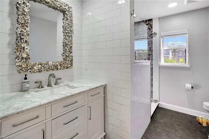 Bathroom featuring tile patterned flooring, vanity and walk in shower
