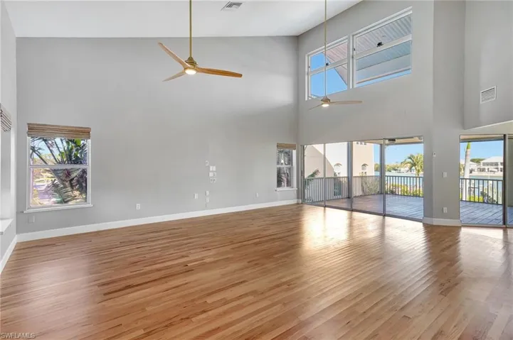 Unfurnished living room with plenty of natural light, light wood-type flooring, and high vaulted ceiling