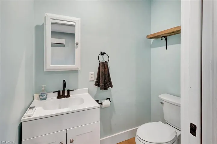 Bathroom with vanity, toilet, and a wall mounted AC
