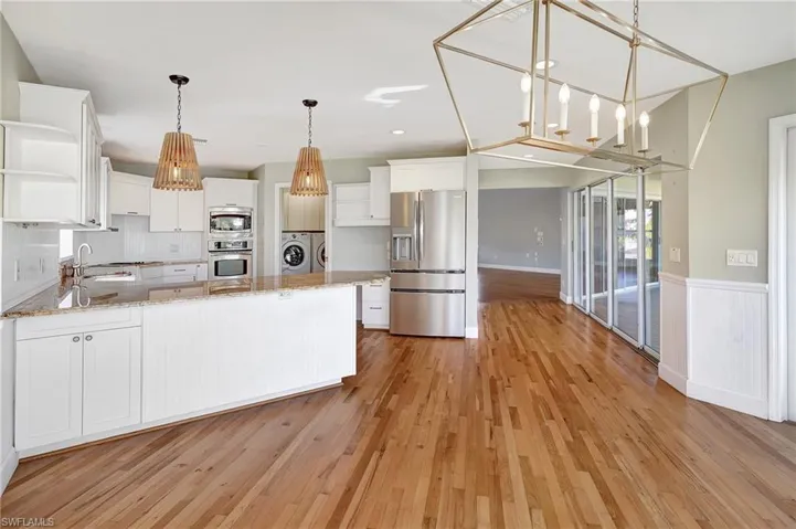 Kitchen with white cabinets, light wood flooring, and stainless steel appliances