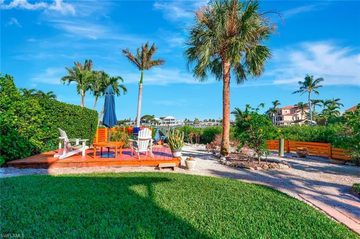 Outdoor patio and beautifully landscaped yard leading to boat dock