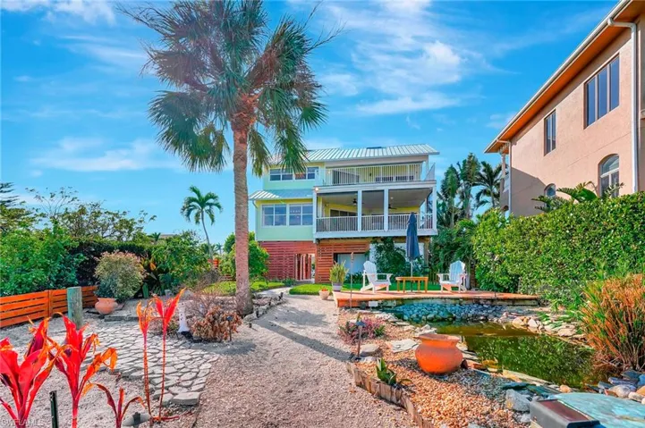Rear view of house featuring patio, deck, pond, and 2 balconies