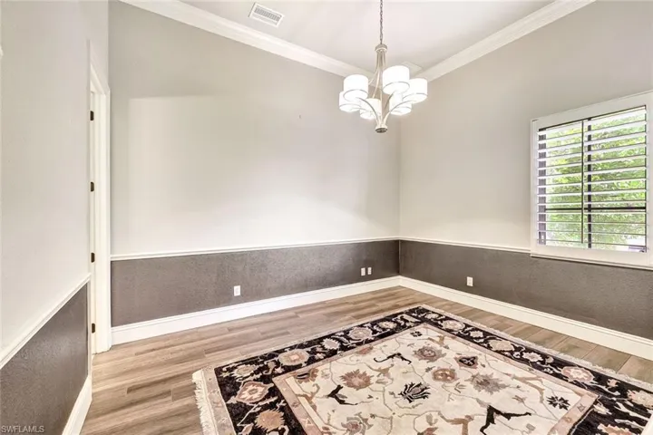 Spare room featuring ornamental molding, light wood-type flooring, and a notable chandelier