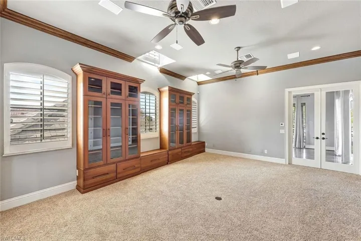 Unfurnished living room featuring light colored carpet, ceiling fan, french doors, and crown molding