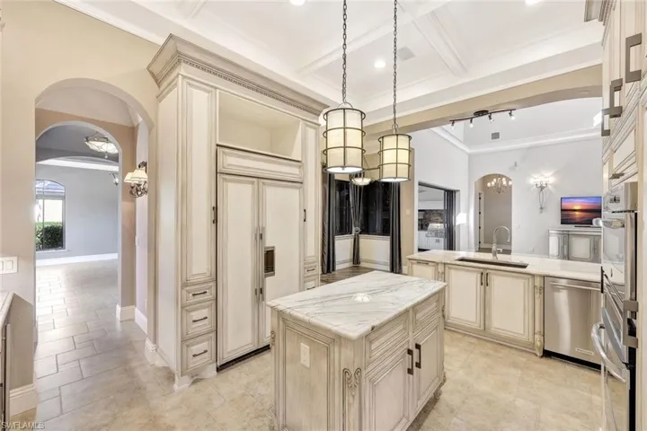 Kitchen with sink, cream cabinets, a center island, and decorative light fixtures