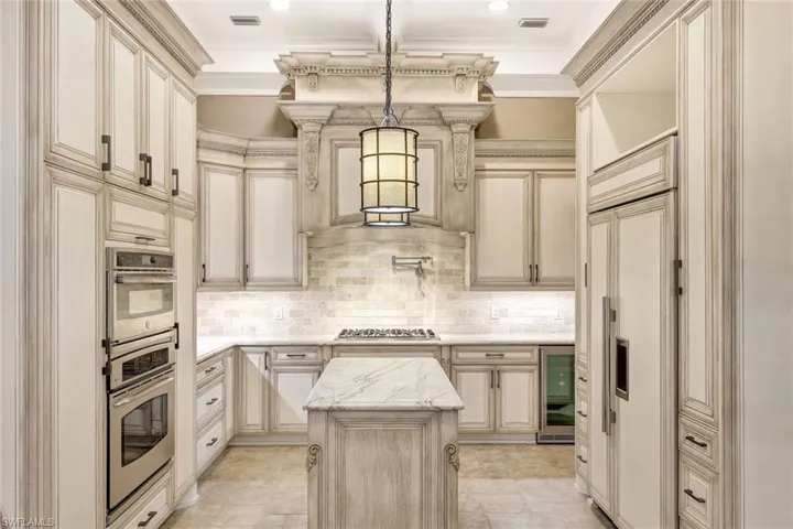 Kitchen featuring hanging light fixtures, decorative backsplash, a kitchen island, wine cooler, and appliances with stainless steel finishes