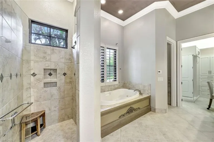 Bathroom featuring tile patterned flooring, crown molding, and plus walk in shower