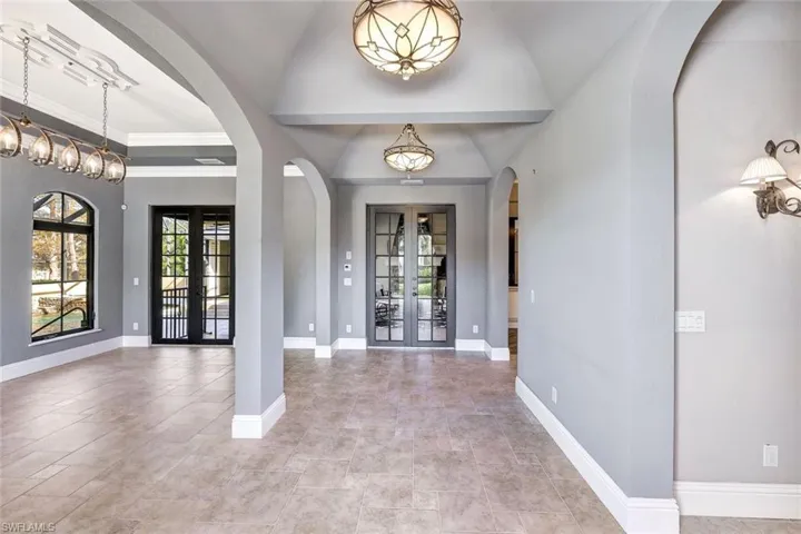Foyer featuring vaulted ceiling, french doors, and a chandelier