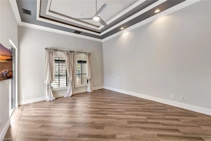 Unfurnished room featuring a towering ceiling, a raised ceiling, ceiling fan, and crown molding