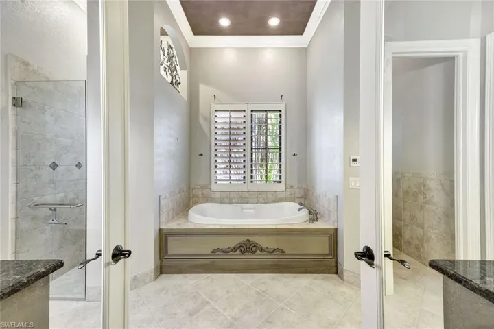 Bathroom with french doors, tile patterned floors, crown molding, and a tub
