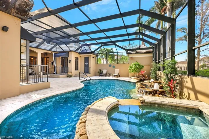 View of swimming pool featuring a patio, glass enclosure, and an in ground hot tub