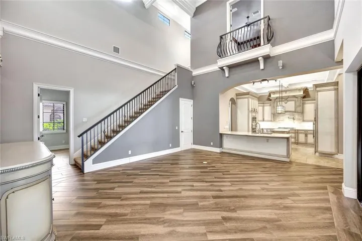 Unfurnished living room featuring a high ceiling, sink, crown molding, and hardwood / wood-style floors