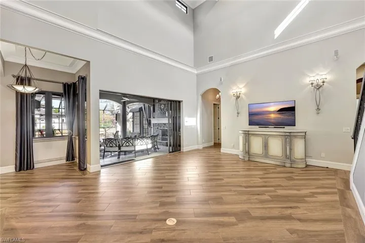 Unfurnished living room featuring a towering ceiling, ornamental molding, and hardwood / wood-style floors