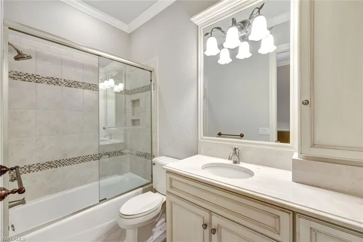 Full bathroom featuring vanity, shower / bath combination with glass door, toilet, and crown molding