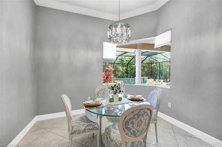 Tiled dining area with baseboards, a chandelier, and crown molding