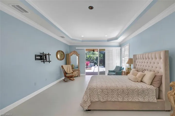 Bedroom with access to exterior, visible vents, baseboards, a tray ceiling, and ornamental molding