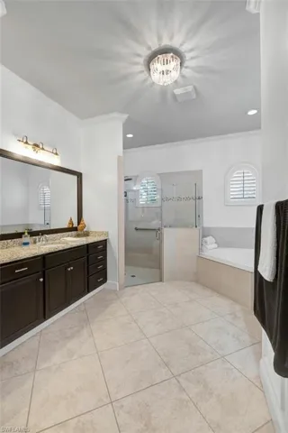 Bathroom with tiled shower, a bath, ornamental molding, and tile patterned flooring