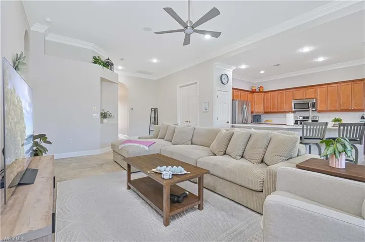Living area with arched walkways, a ceiling fan, crown molding, light wood finished floors, and recessed lighting