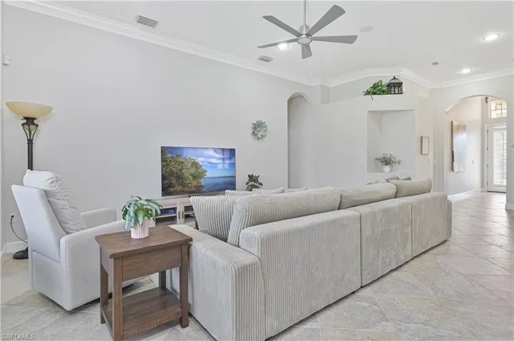 Living room featuring ornamental molding, a ceiling fan, recessed lighting, and arched walkways