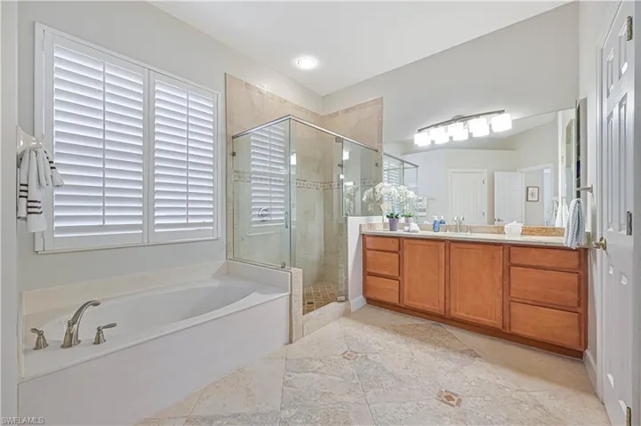 Bathroom featuring a shower stall, vanity, and a garden tub
