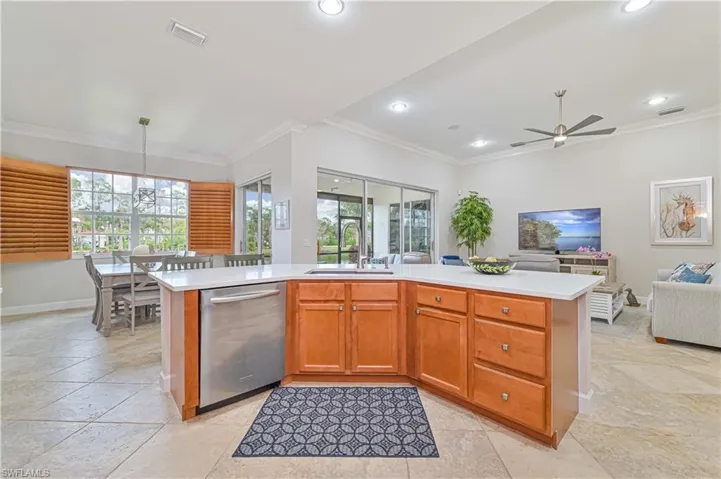 Kitchen with crown molding, open floor plan, an island with sink, dishwasher, and wood finish cabinetry