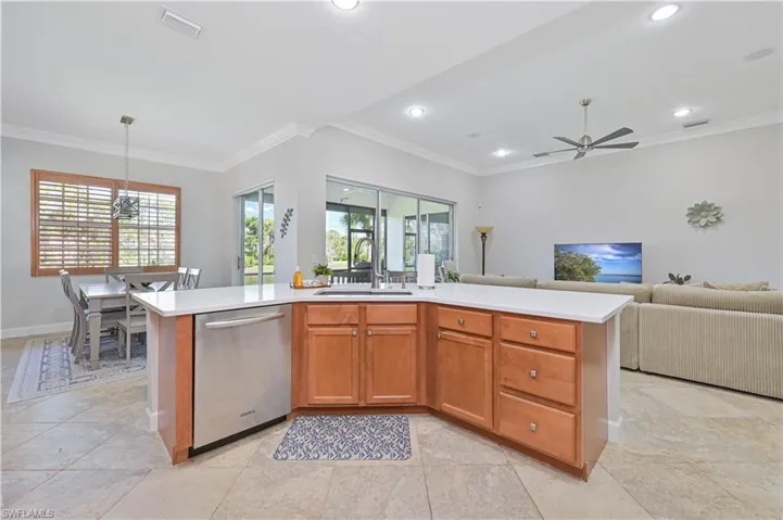 Kitchen featuring an island with sink, open floor plan, stainless steel dishwasher, crown molding, and wood finish cabinets