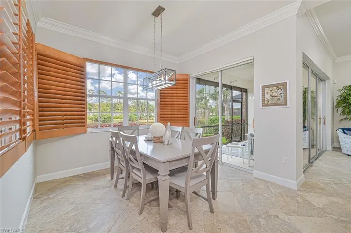 Dining area with ornamental molding, healthy amount of natural light, and light stone finish floors