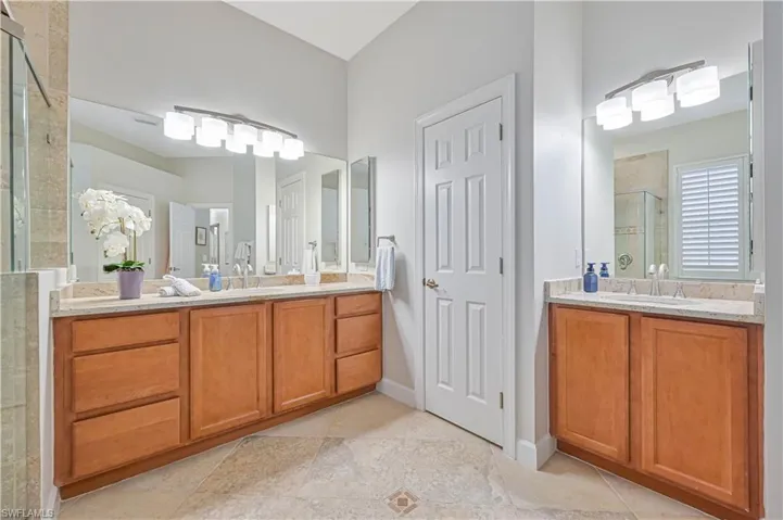 Full bath with a stall shower, two vanities, and light tile patterned flooring