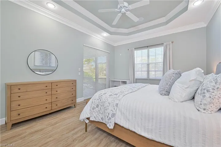 Bedroom with light wood-style flooring, ornamental molding, and a ceiling fan