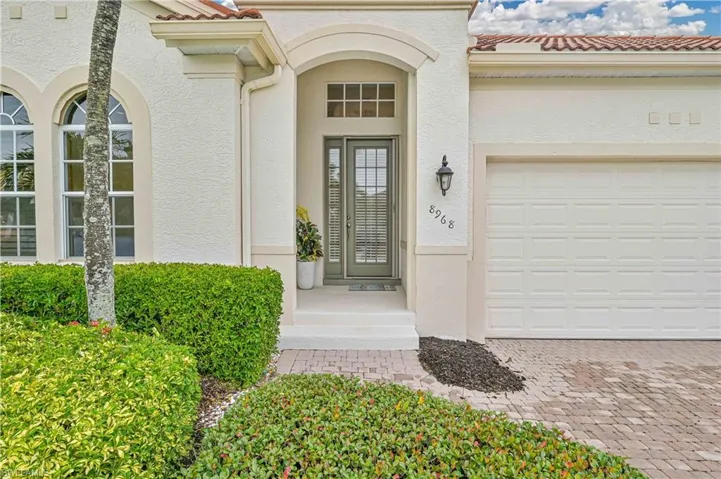 Doorway to property featuring a tile roof, stucco siding, driveway, and a garage