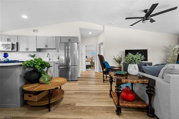 Kitchen with gray cabinetry, stainless steel appliances, lofted ceiling, light wood-style floors, and light countertops
