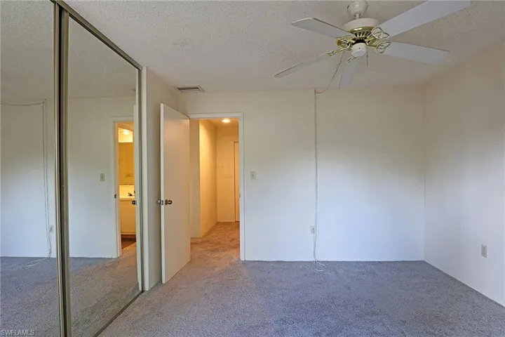 Unfurnished bedroom with carpet, a textured ceiling, ceiling fan, and a closet
