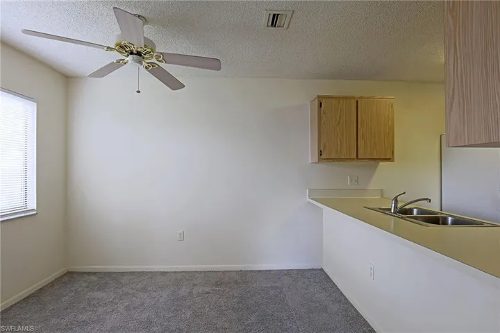 Kitchen with light countertops, a textured ceiling, dark colored carpet, a ceiling fan, and stainless steel fridge