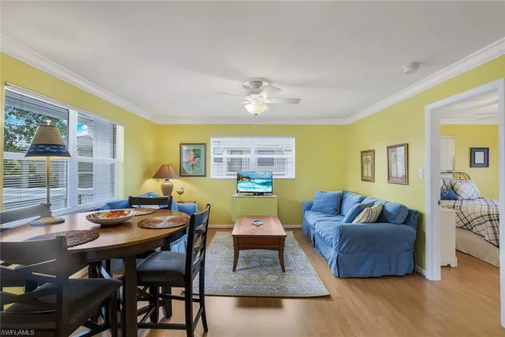 Living room with crown molding, ceiling fan, and light wood-type flooring