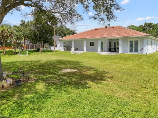 Back of property featuring a patio, stucco siding, a tiled roof, and a lawn