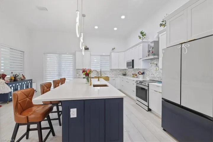 Kitchen featuring white cabinets, appliances with stainless steel finishes, a kitchen bar, ornamental molding, and tasteful backsplash
