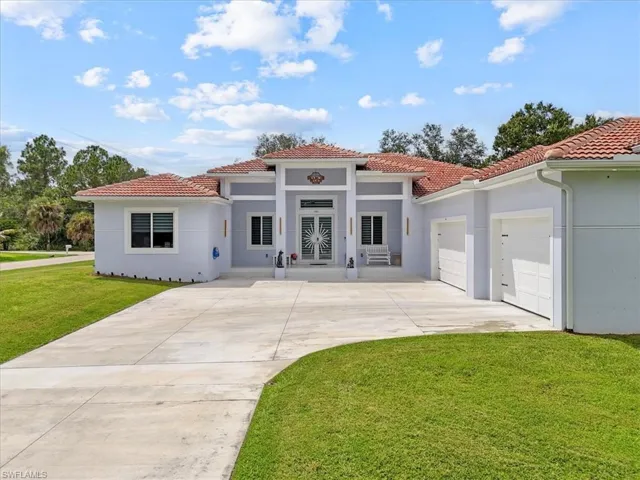Mediterranean / spanish house featuring a tiled roof, stucco siding, concrete driveway, and a front yard
