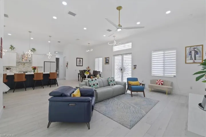Living area with light wood-style floors, recessed lighting, a ceiling fan, a chandelier, and ornamental molding