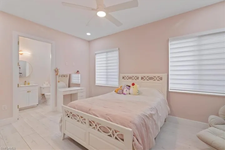 Bedroom with light wood-type flooring, a ceiling fan, connected bathroom, and recessed lighting