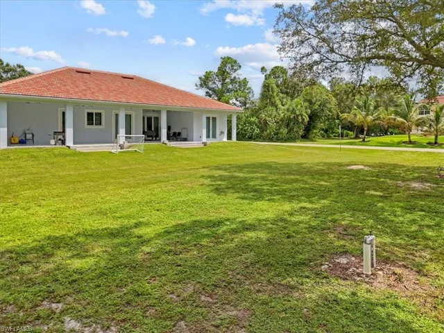 Back of house featuring a patio, stucco siding, a yard, and a tile roof