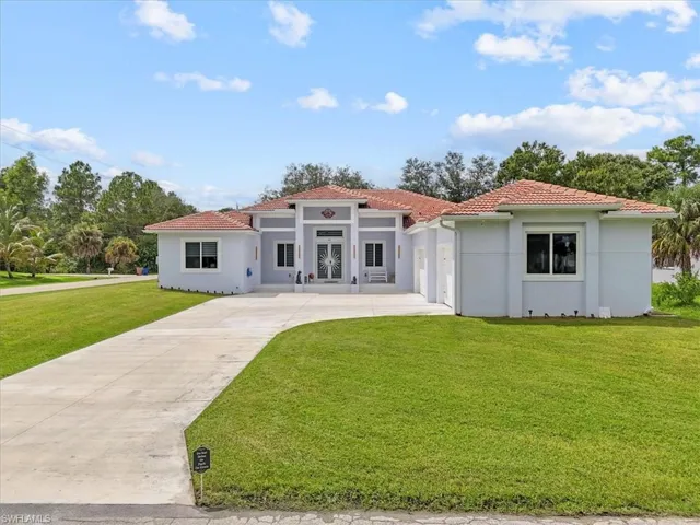Mediterranean / spanish-style house with a front yard, driveway, stucco siding, and a tiled roof